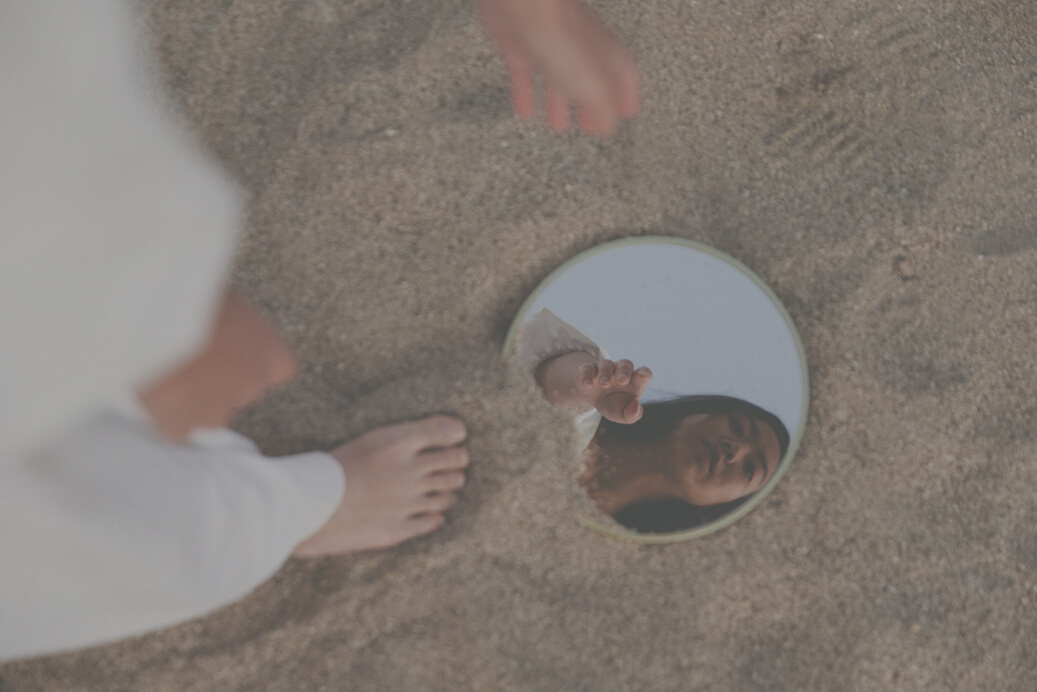 Woman Looking at Compact Mirror at the Beach